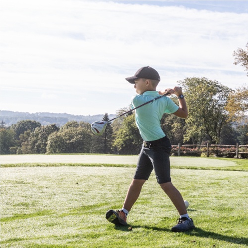child swinging golf club on the greens of Brookside Country Club